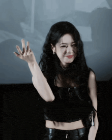 a woman with long black hair is wearing a black crop top and leather pants