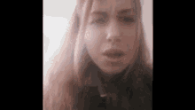 a close up of a woman 's face with long red hair looking at the camera .