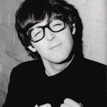 a young man wearing glasses and a black shirt