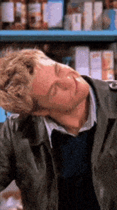 a man in a black leather jacket is sleeping in a store