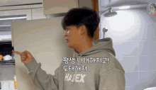 a man wearing a hoodie that says haex is pointing at something