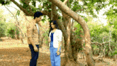 a man and a woman standing under a tree in the woods