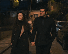 a man and a woman holding hands on a street