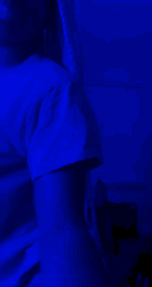 a woman in a blue shirt is standing in a dark room