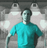 a man wearing a blue shirt is standing in front of a stage