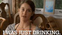 a woman is sitting in a chair with the words " i was just drinking " above her