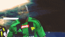 a soccer player wearing a green jersey with a betelle logo on the front