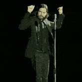 a man in a suit and tie stands in front of a microphone
