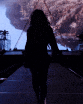 a silhouette of a woman walking in front of a large screen