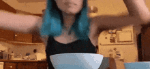 a woman with blue hair is sitting at a table with a bowl of food .