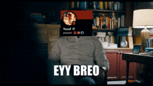a man sitting in front of a bookshelf has a picture of yusuf on his head