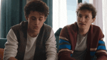two young men sitting next to each other with one wearing a sweater that says ' abercrombie & fitch ' on it