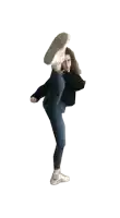 a woman is kicking her leg up in the air while wearing jeans and white sneakers .