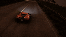 a red sports car is driving down the road at night