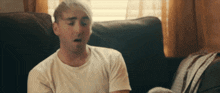 a man in a white shirt is sitting on a couch