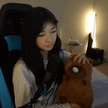 a woman holding a stuffed animal with a white ball on its head and a shirt that says nintendo