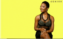 a woman is sitting in front of a yellow background that says genius on it