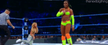 a woman in a neon green outfit is standing in a wrestling ring with a referee