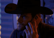 a man wearing a cowboy hat is talking on his phone