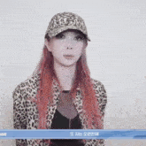 a woman wearing a leopard print jacket and a baseball cap with the name ami on the bottom right