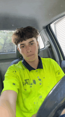 a young man wearing a neon yellow shirt that says me is sitting in a car