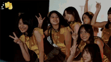 a group of young women are posing for a picture and making peace signs while dancing .