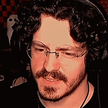 a man with glasses and a beard is wearing headphones and smiling .