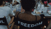 a woman sits in a chair with the word freedom on the back of her shirt