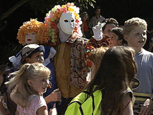 a group of children are gathered around a man wearing a clown costume