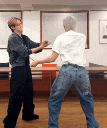 a man in a white shirt stands next to another man in jeans