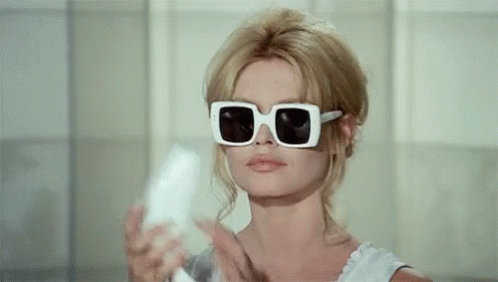Glamorous 1970s blonde, wearing big sunglasses, picking up an old school landline handset.