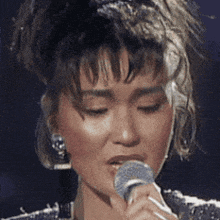 a woman is singing into a microphone with her eyes closed