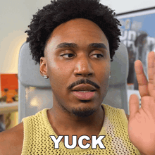 a man in a yellow tank top with the word yuck on it