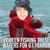 a man in a red jacket is fishing and giving a thumbs up sign