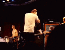 a man singing into a microphone while playing a guitar on stage