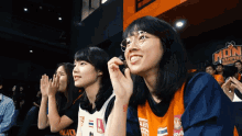 a woman wearing a jersey that says mon vampire watches a game