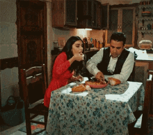 a man and a woman are sitting at a table eating