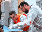two men are working on a patient in a room with the number 15 on the wall behind them