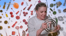 a woman is holding a trophy in front of a wall filled with food .