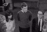 a man and a woman are standing next to each other in a black and white photo .