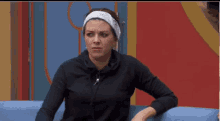 a woman wearing a headband is sitting on a couch and making a funny face .