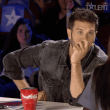 a man sits at a table with a coca cola cup on it