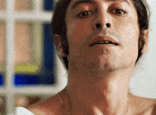 a close up of a man 's face with his mouth open and a necklace around his neck .