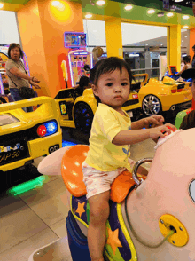 a little girl is riding a toy car with a license plate that reads ap 50