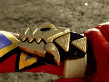 a person wearing a red glove is holding a gold item that looks like a dinosaur