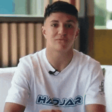 a young man wearing a white t-shirt with the word hajar on it .