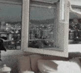 a person is opening a window in a living room with a view of a city .