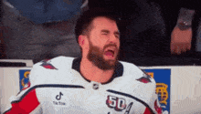 a hockey player with a beard is crying while sitting on the bench during a game .