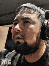 a man with a beard wearing headphones and a black shirt with the word me on it