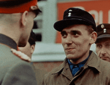 a man wearing a hat with the letter o on it talks to another man